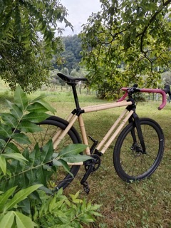 La 5/1bln — un telaio di bici in bambù fatto a mano con dettagli rosa, in un frutteto verde della Valtellina